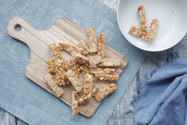 Sesame date sticks on a small board over blue linen