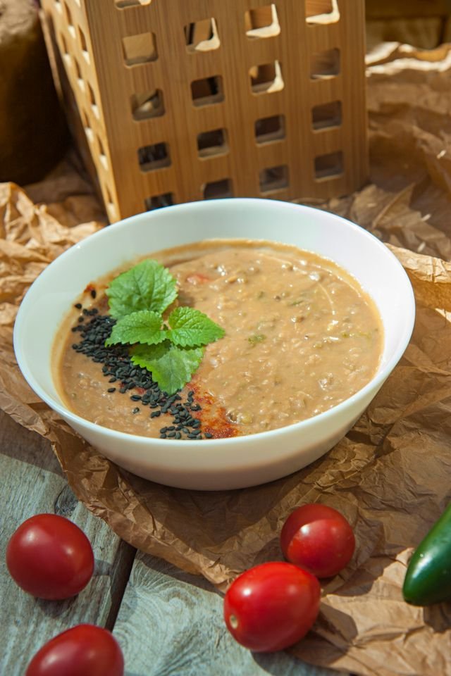 Creamy tan tomato almond soup with black sesame and mint, cherry tomatoes