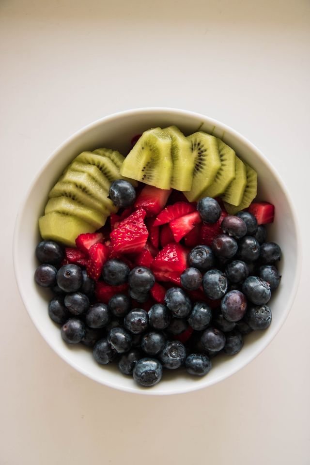 White bowl of blueberries, raspberries and kiwi slices