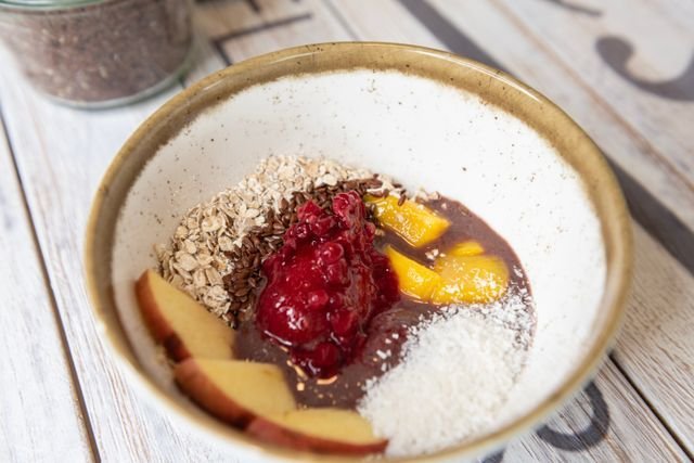 Speckled bowl with raspberry sorbet, mango, apple slices, oats and coconut