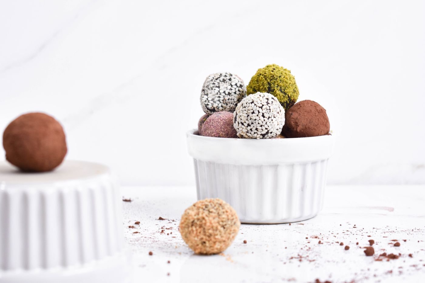 Rainbow coated truffles in white ramekins: pistachio, coconut, beet and cacao