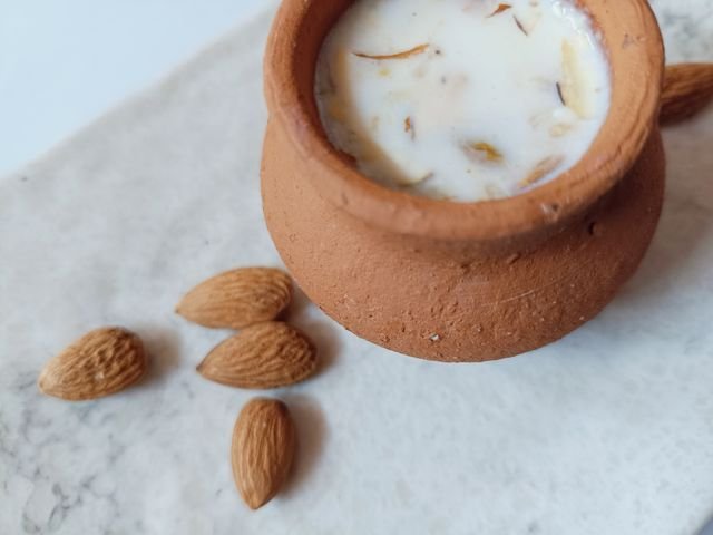 Saffron almond milk in a clay pot with almonds