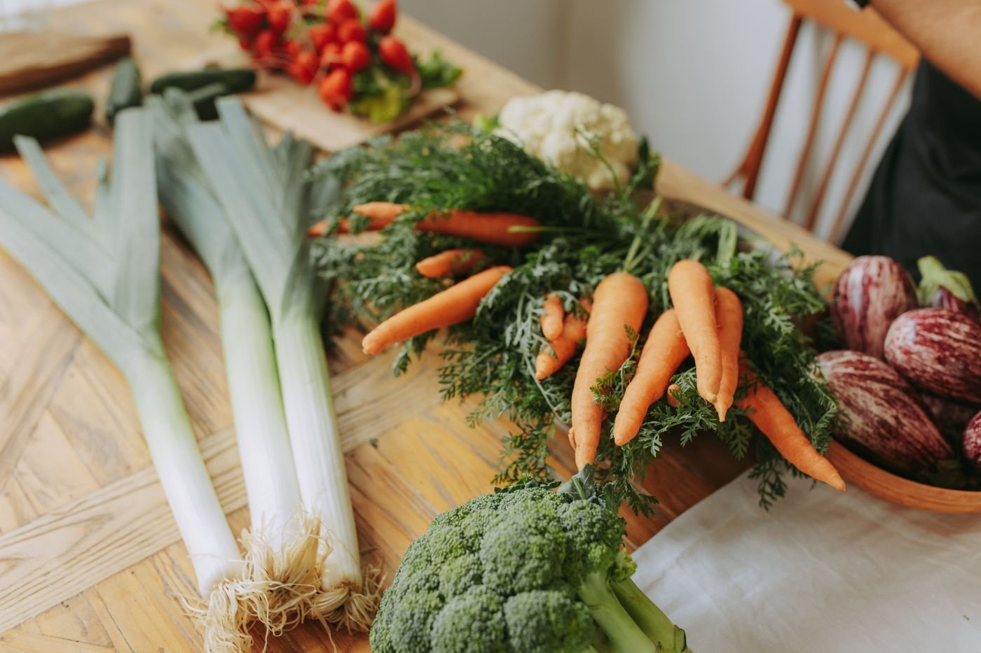 Leeks, carrots, broccoli and striped eggplant on a kitchen table