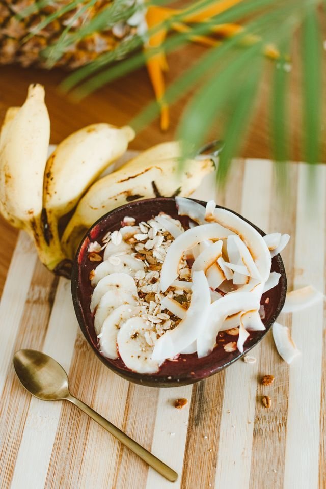 Coconut shell bowl heaped with coconut ribbons and banana on striped cloth